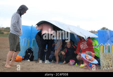 Une famille se protège du temps sur la plage de Skegness, car la pluie, le vent et les avertissements météorologiques ont mis fin à la vague de chaleur de juin. Banque D'Images