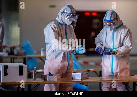 28 juin 2020, Rhénanie-du-Nord-Westphalie, Gütersloh : les aides en combinaisons de protection désinfectent leurs gants après utilisation. Sur le site de l'ancien aéroport militaire de Gütersloh, les forces armées allemandes, ainsi que des organisations humanitaires, ont mis en place une station de test où les gens peuvent être testés pour Covid-19 après l'épidémie coronarienne à l'usine de viande de Tönnies. Photo: David Inderlied/dpa Banque D'Images