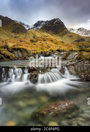 Petit ruisseau de cascade en cascade à Deepdale Beck dans le parc national du district de Lake avec neige sur les sommets de montagne. Banque D'Images