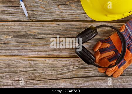 Équipement de sécurité de construction standard casque antibruit cuir casque de sécurité gants de protection sur table en bois vue du dessus Banque D'Images