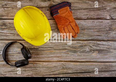 Équipement norme de sécurité construction protections auditives de sécurité cuir casque de sécurité gants de protection sur table en bois vue du dessus Banque D'Images