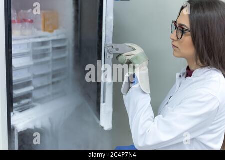 Jeune femme avec un travail scientifique de recherche de l'azote liquide froid dans un laboratoire. La génétique et les études et les recherches pharmaceutiques. Banque D'Images