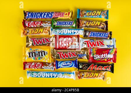 Ukraine, Kiev - 23 mars 2020 : un bouquet de barres de chocolat, dont des Snickers, Twix, Milka, KitKat, Lion, M&M, Bounty, sur fond jaune. Banque D'Images