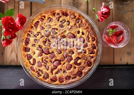 Clafoutis à la cerise sur un fond en bois, dessert traditionnel français aux fruits doux. Banque D'Images