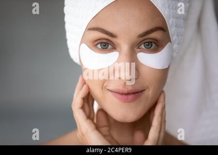 Jeune femme look dans le miroir application sous les cellules oculaires Banque D'Images