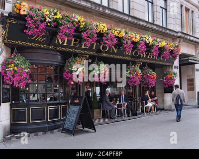 Les pubs londoniens disposent souvent d'un coin salon extérieur décoré de paniers de fleurs suspendus colorés en été. Banque D'Images