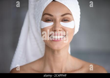 Portrait de la jeune femme utilisant des timbres pour le dessous de l'oeil Banque D'Images