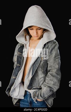 Garçon de 11 ans avec pull à capuche et veste jean sur fond noir Banque D'Images