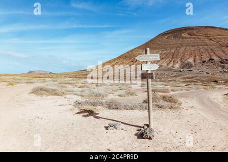 Un panneau en bois au milieu de la Graciosa, à une jonction de pistes poussiéreuses, pointant vers divers endroits, Île Graciosa, îles Canaries, Espagne Banque D'Images