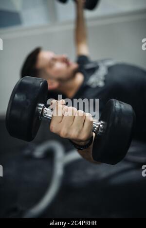 Gros plan un jeune homme qui lève des poids dans une salle de sport. Banque D'Images