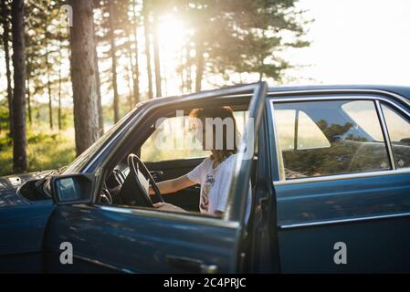 Femme assise dans une voiture brisée garée. Banque D'Images
