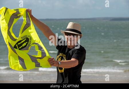 Southsea, Hampshire, Angleterre, Royaume-Uni. Juin 2020. Femme portant un t-shirt social et garde votre distance à la veste haute vis lors d'une journée venteuse sur la plage A. Banque D'Images