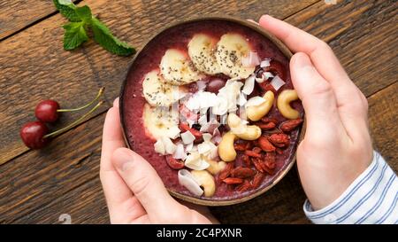 Bol d'açai Superfood dans les mains des hommes avec garnitures Superfood. Alimentation saine paléovégétalienne Banque D'Images