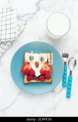 Toasts pour le petit déjeuner pour les enfants en forme de chouette chouette drôle. Petit déjeuner pour enfants sur une assiette bleue, vue du dessus, orientation verticale Banque D'Images