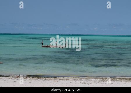 Trois hommes sur une boude bois sur l'océan Indien au large de la côte de Jambiani à Zanzibar, Tanzanie Banque D'Images