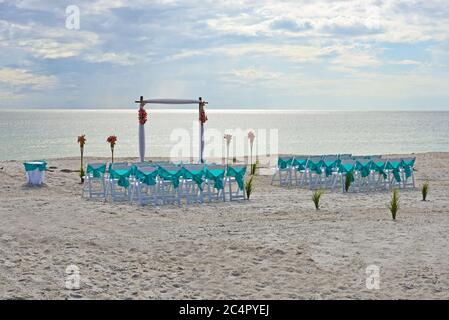 Chaises disposées sur la plage en préparation pour un mariage en soirée Banque D'Images