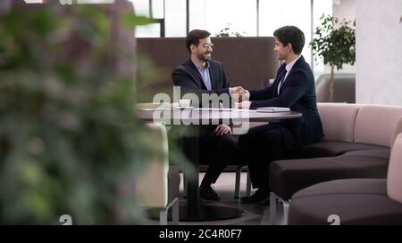 Deux hommes d'affaires souriants se secouent la main après une réunion réussie Banque D'Images