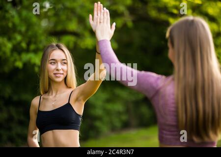 Deux jeunes femmes sportives se donnant un haut cinq avant l'entraînement à l'extérieur Banque D'Images