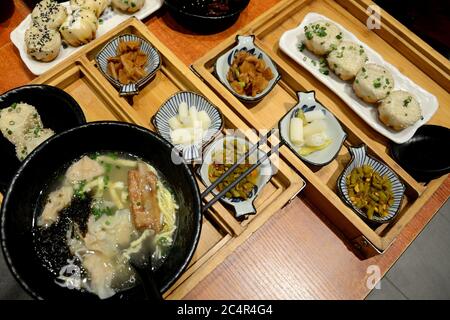 Cuisine chinoise typique sur le tachechi à Guangzhou, Chine. Bol de soupe avec nouilles et côtes levées, en-cas épicés - haricots, ail et boulettes chinoises 'baozi'. Banque D'Images