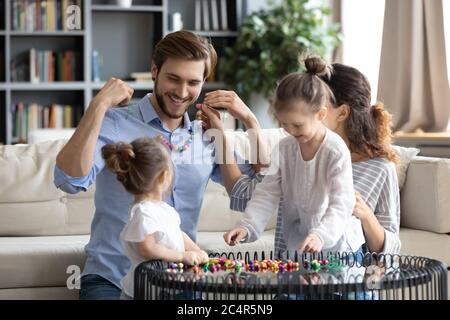 Joyeux jeune famille faisant des bijoux en bois coloré perles ensemble Banque D'Images