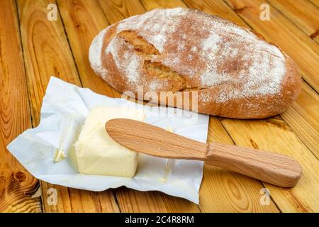 Pain frais et beurre savoureux sur une table en bois. Pain dans la cuisine. Arrière-plan sombre. Banque D'Images