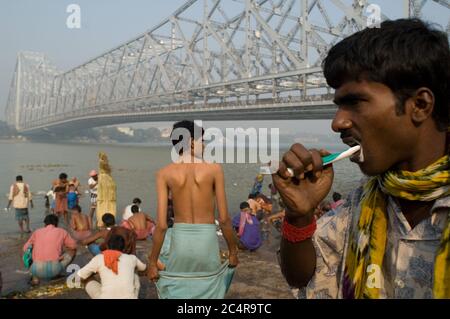 Chaque matin, les gens se rassemblent au bain près du pont de Haora pour nettoyer leur corps et laver leurs vêtements dans les Hugli. Banque D'Images