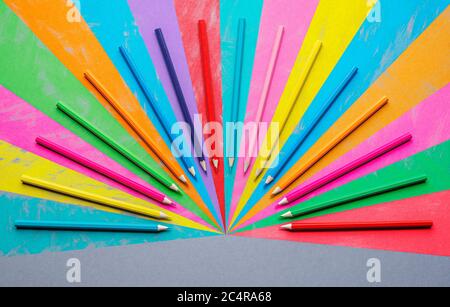 Crayon à dessin sur un papier gris et les crayons en bois disposés en forme de ventilateur. Fournitures scolaires. Vue du dessus de l'arrière-plan coloré. Banque D'Images