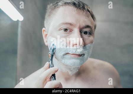 Guy regarde dans le miroir avant de se raser Banque D'Images