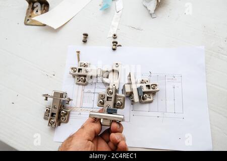 Paris, France - 8 juin 2020: Man Hand POV tenant regardant la nouvelle charnière de tiroir Ikea avec un schéma de nouveau mur avec des portes pendant la reconstruction Banque D'Images