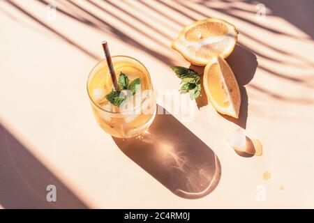 Limonade fraîche avec feuilles de menthe et glaçons sur fond jaune, ombres nettes, vue du dessus. Banque D'Images