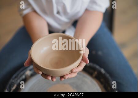 Femme travaillant sur la roue de potiers faisant des plats avec leurs propres mains. Photo en gros plan de l'argile de moulage sale mains Banque D'Images