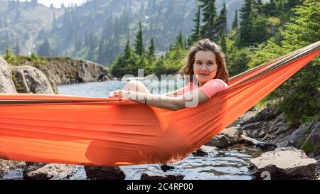 La femme se détend dans un hamac au bord du lac alpin sur les vacances locales Banque D'Images