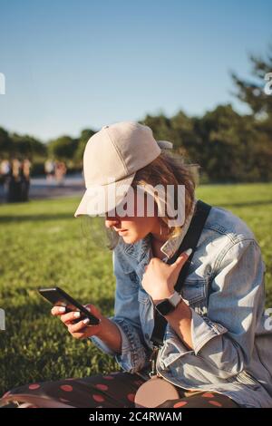 Belle fille blonde dans un chapeau avec les cheveux courts est assis dans un groupe de filles et regardant loin. Mise au point sélective. Banque D'Images