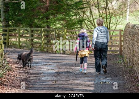 Une mère et une fille marchent un chien noir le long d'une piste de campagne. Banque D'Images