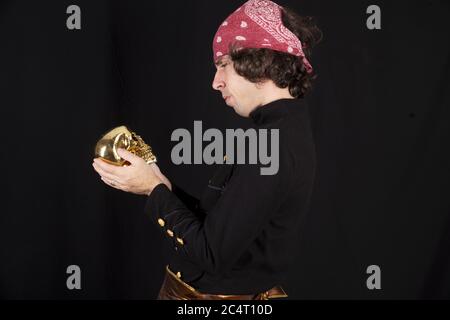 Homme en costume de pirate tenant un crâne doré Banque D'Images