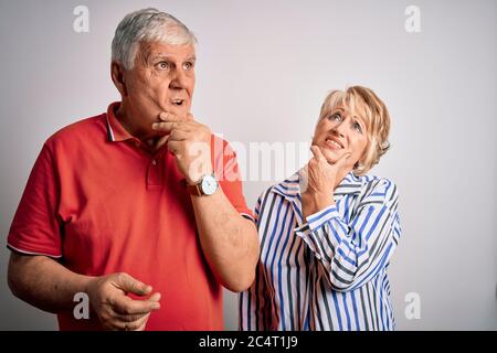 Couple senior beau debout ensemble sur fond blanc isolé pensant inquiet à une question, inquiet et nerveux avec la main sur le menton Banque D'Images
