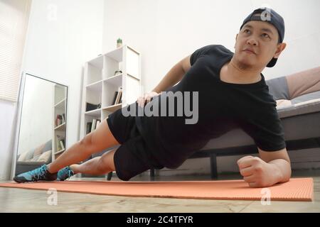 Asiatique homme faisant de l'exercice à la maison pour rester en bonne santé sur le nouveau mode de vie normal, intérieur maison concept d'entraînement, abdominaux de base d'entraînement abs Banque D'Images