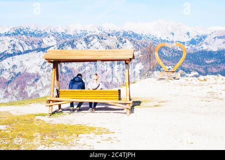 Jeune couple de touristes assis sur un banc et regardant le beau paysage de Vogel, Slovénie. Banque D'Images