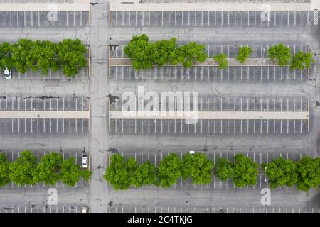 Vue abstraite de drone regardant vers le bas sur un stationnement en asphalte presque vide avec des rangées d'arbres Banque D'Images