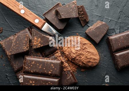 Chocolat savoureux et cuillère à poudre sur fond noir Banque D'Images