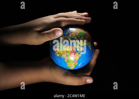 Les enfants tiennent le globe terrestre sur fond noir. Globe terrestre isolé sur fond noir. Globe scolaire sur fond noir. Banque D'Images