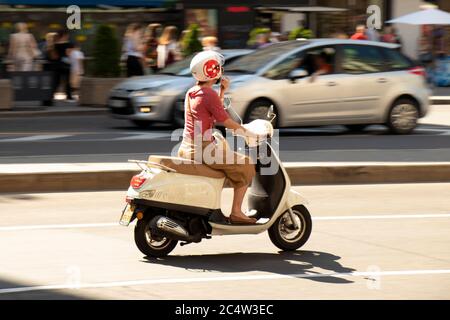 Belgrade, Serbie - 25 juin 2019 : flou de mouvement d'une femme à cheval sur un vespa dans la ville circulation de rue en été chaleur, panoramique tourné Banque D'Images