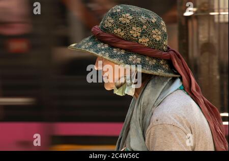 Belgrade, Serbie - 25 juin 2020 : femme âgée d'époque portant des masques chirurgicaux sales et un chapeau avec un foulard marchant dans la rue de la ville, gros plan Banque D'Images