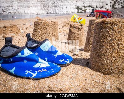 châteaux de sable avec chaussures de plage pour enfants sur une plage de sable Banque D'Images