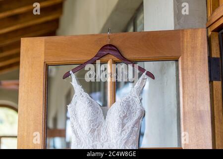 Gros plan d'une robe de mariage en dentelle blanche accrochée de la porte Banque D'Images