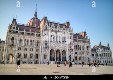 Le bâtiment du paliament hongrois avec des gens qui marchent autour de la place, Budapest. Banque D'Images