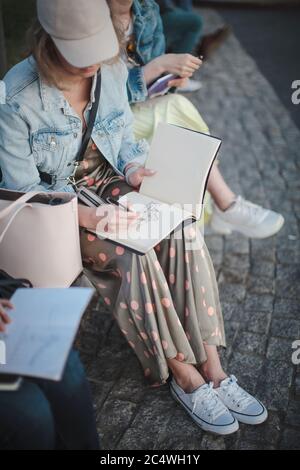 Jeune fille belle attire dans un parc dans un groupe. Contour dans un carnet d'esquisses. Banque D'Images