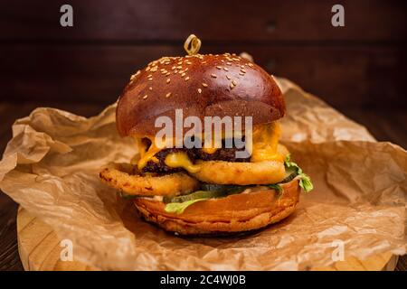 Un cheeseburger avec rondelles d'oignon sur une planche de bois Banque D'Images