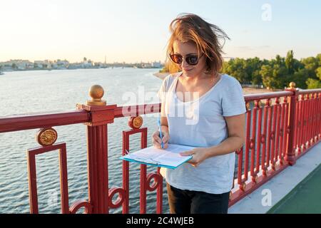 Femme d'affaires travaillant à l'extérieur, femme avec un document papier sur une planchette à pince Banque D'Images