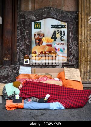 Un homme sans abri dormant à l'extérieur d'un restaurant McDonalds, à l'angle de la Calle de la Montera et de la Gran via, Madrid, Espagne. Banque D'Images